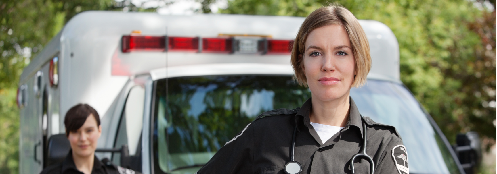 Image of 2 women standing Infront of an non emergency patient transfer vehicle 